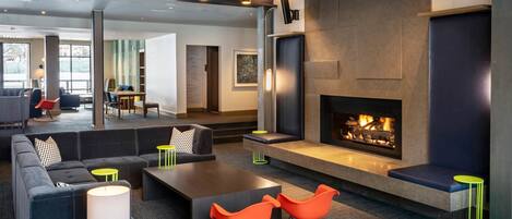 Un espace de détente moderne doté d’une cheminée, de différents types de sièges et d’un éclairage d’ambiance.