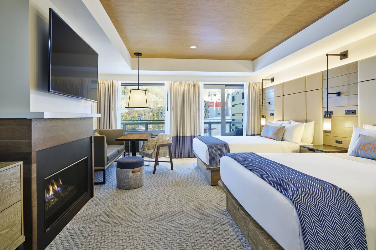 Une chambre d’hôtel moderne équipée d’une cheminée, d’une télévision, d’un canapé, d’une table à manger et de deux lits.