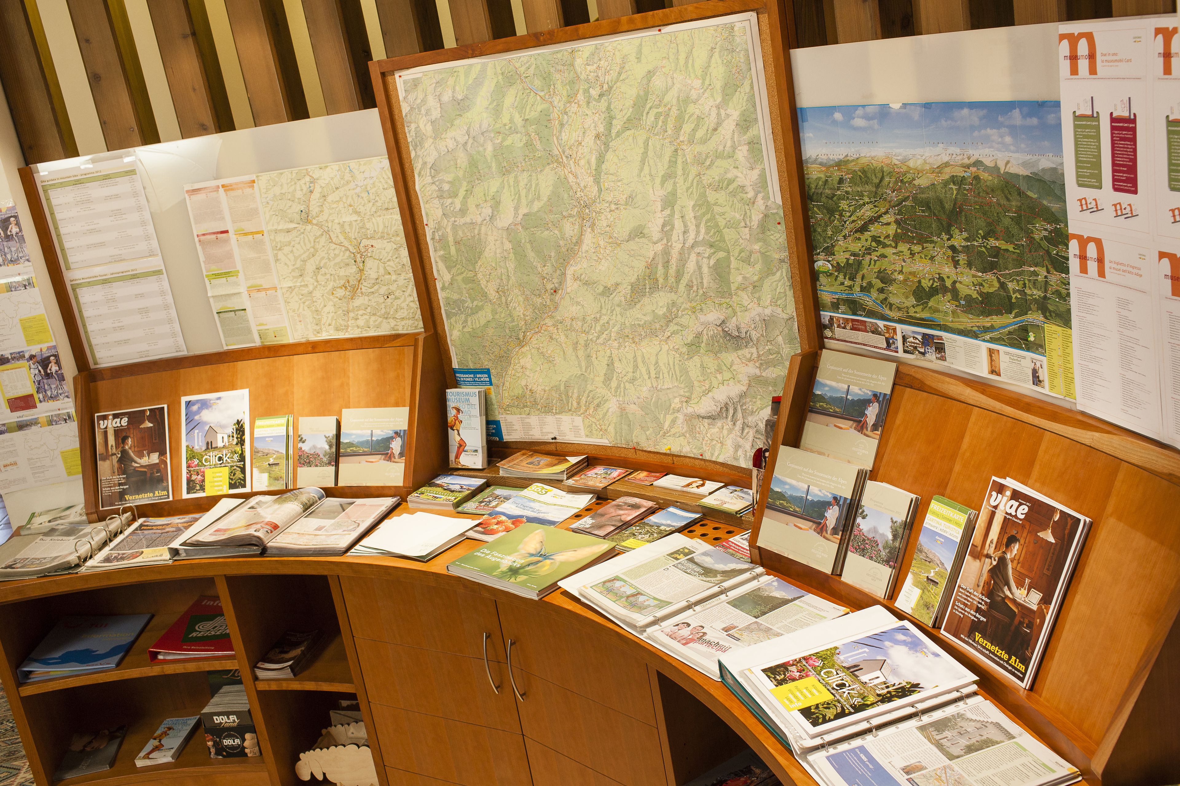 Exposição de folhetos de viagem e mapas em um quiosque de madeira.