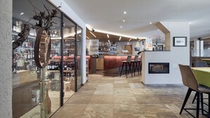 A modern interior with a bar area, seating, and a fireplace. - Vinumhotel Feldthurnerhof (Velturno)