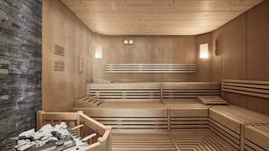 A sauna with wooden benches and a stone wall. - Vinumhotel Feldthurnerhof (Velturno)