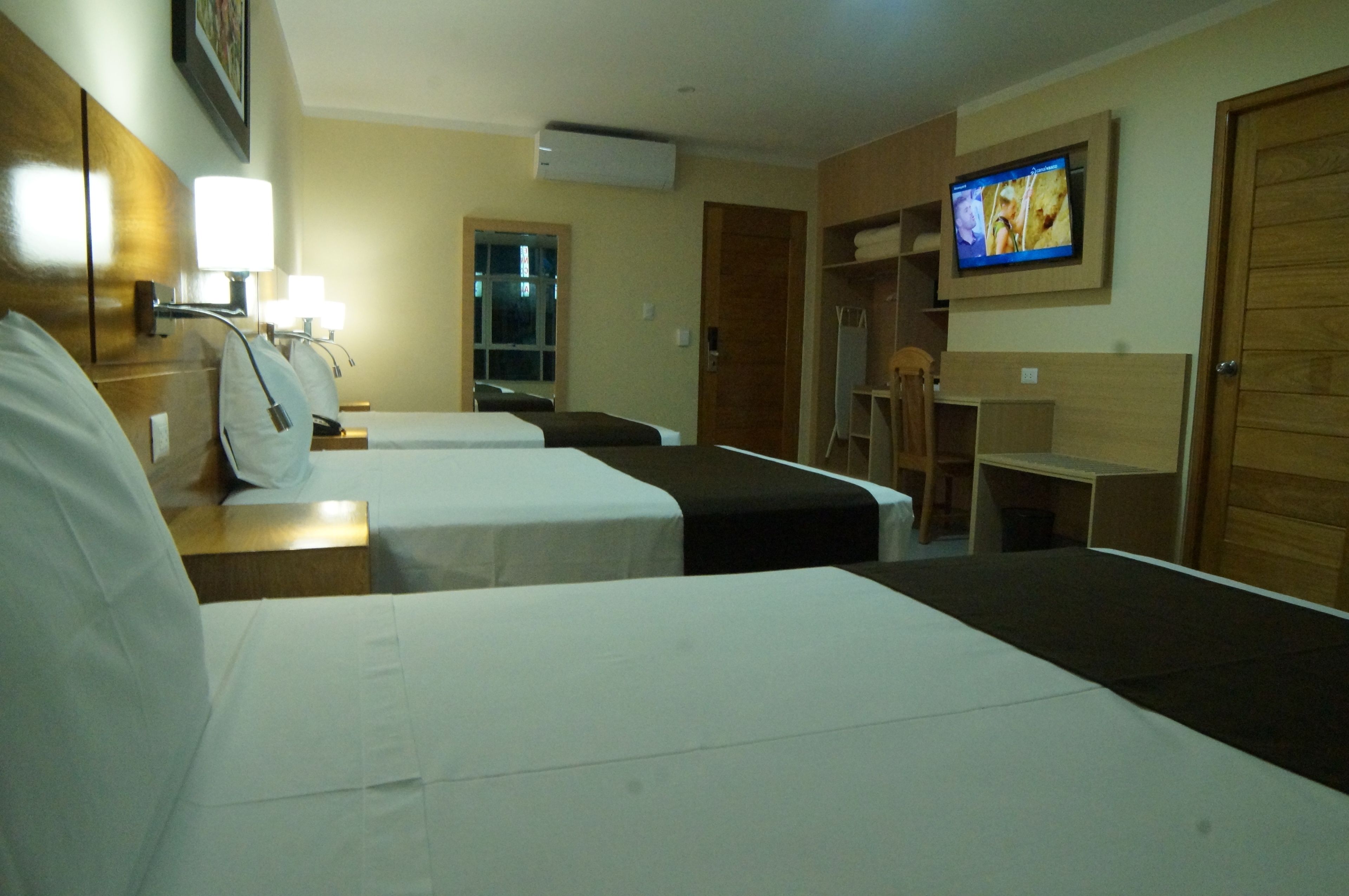 Una habitación de hotel con dos camas, un escritorio, televisor y ventana.