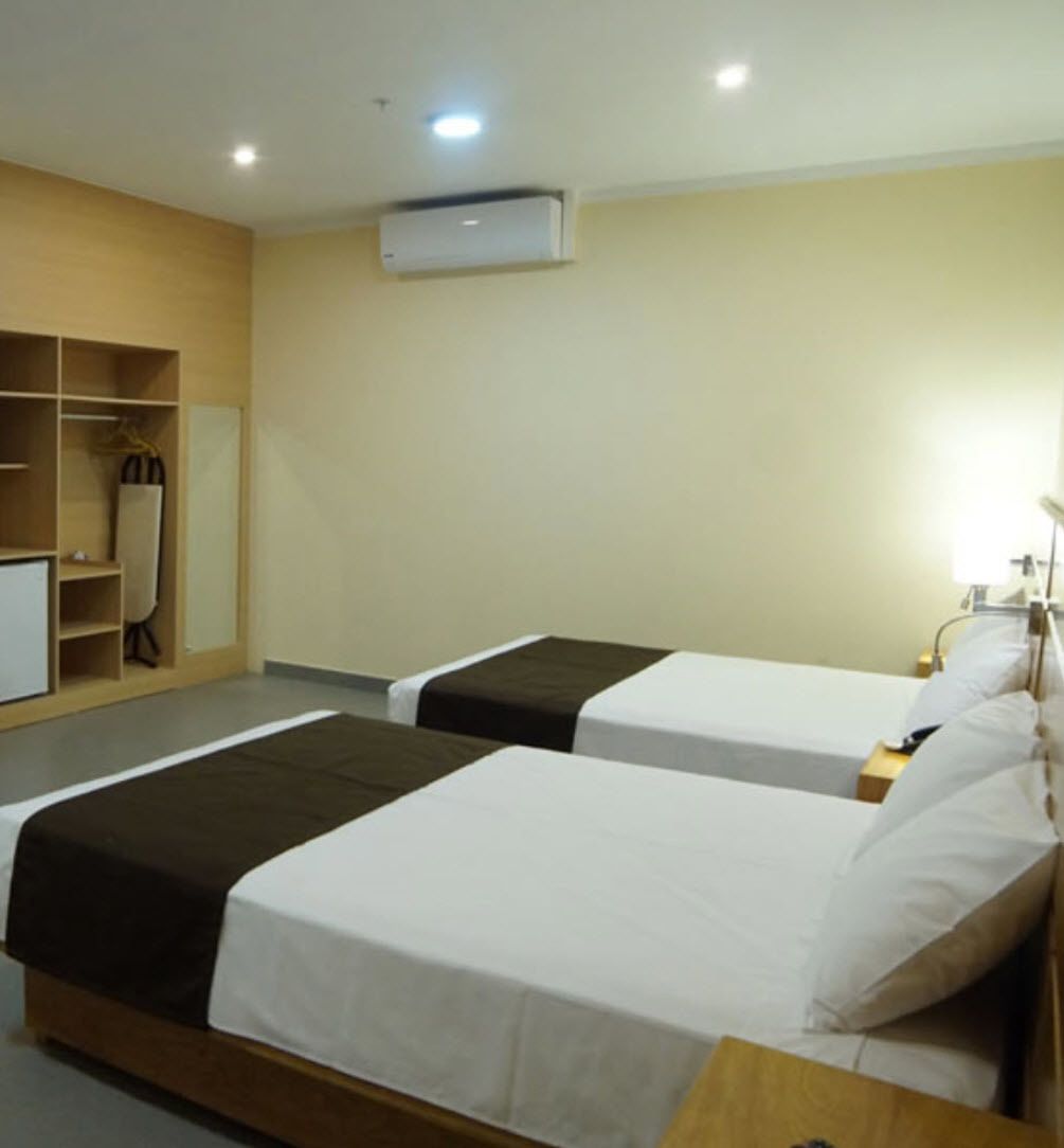 Une chambre d’hôtel avec deux lits, une armoire, un bureau et un appareil de climatisation.