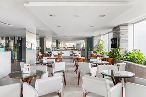 A modern hotel lobby with a central bar area, seating arrangements, and large windows providing natural light. - Citi Hotel Express Caruaru (Caruaru)