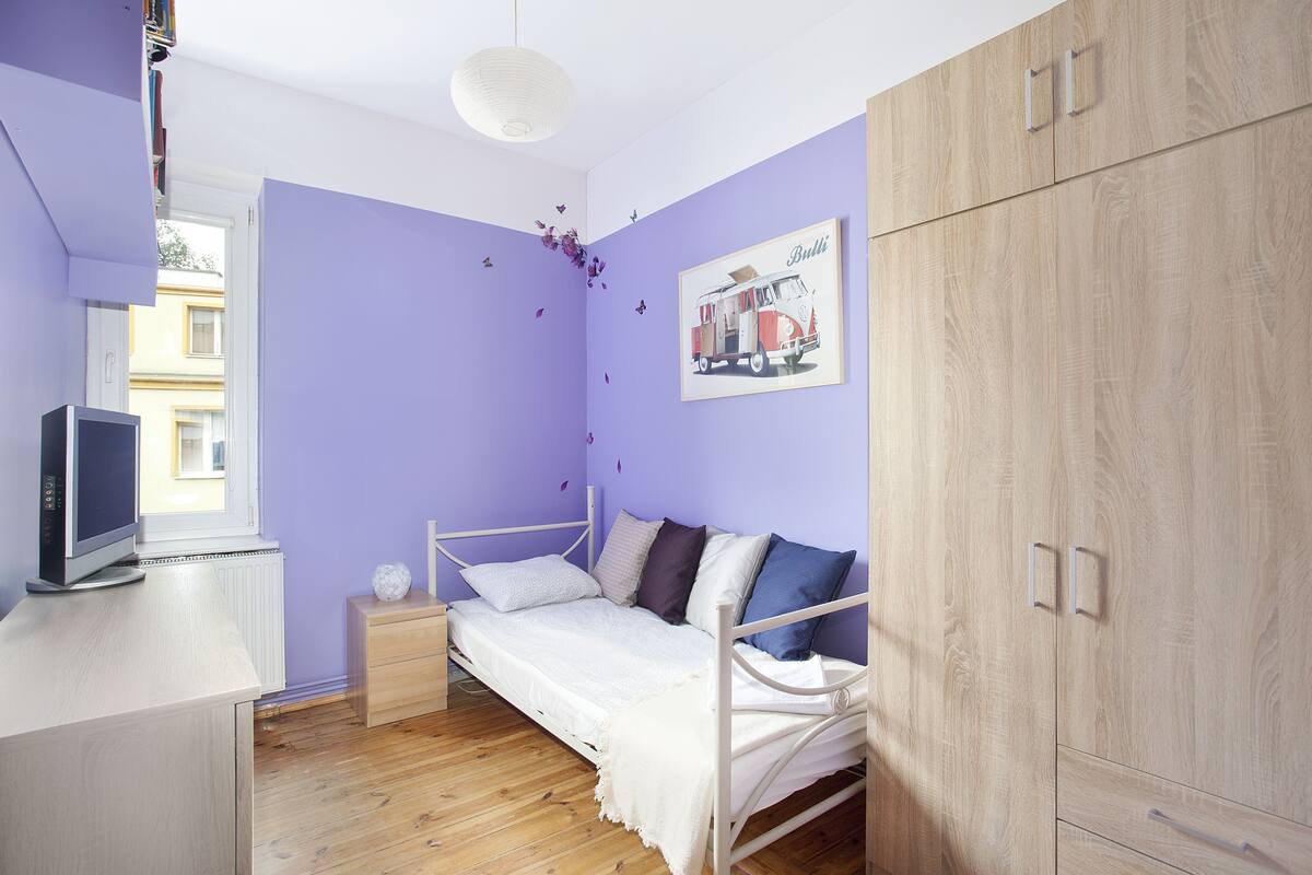 A bedroom with a bed, bedside table, TV, and wardrobe.