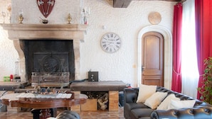 Un salon chaleureux avec une cheminée, un canapé en cuir et une table basse ronde.