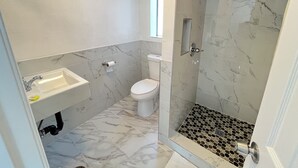 A bathroom with a shower, toilet, sink, and marble flooring. - Griffith Park Motel - LA Hollywood Area (Glendale)
