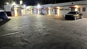 A hotel with a spacious parking lot, multiple rooms with red awnings, and a well-lit exterior. - Griffith Park Motel - LA Hollywood Area (Glendale)