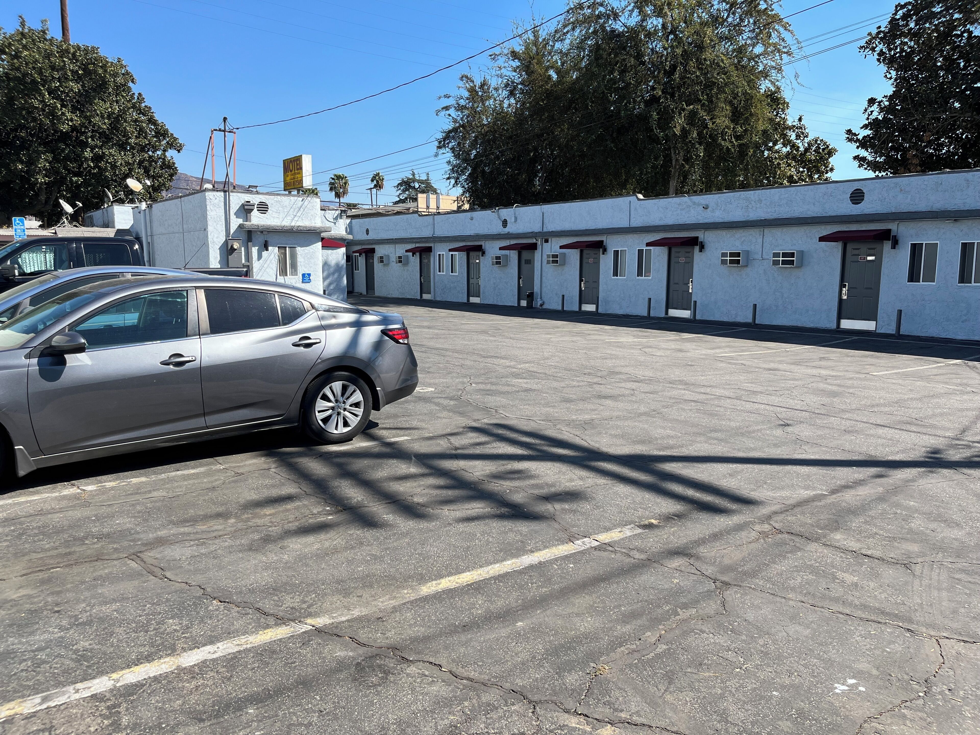 Un estacionamiento con un coche plateado estacionado al frente.