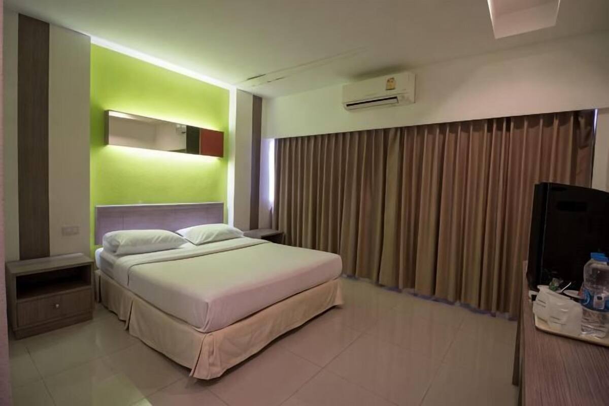Una habitación de hotel con una cama, televisión, escritorio y espejo.