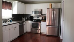 A modern kitchen with white cabinets, stainless steel appliances, and a wooden countertop.