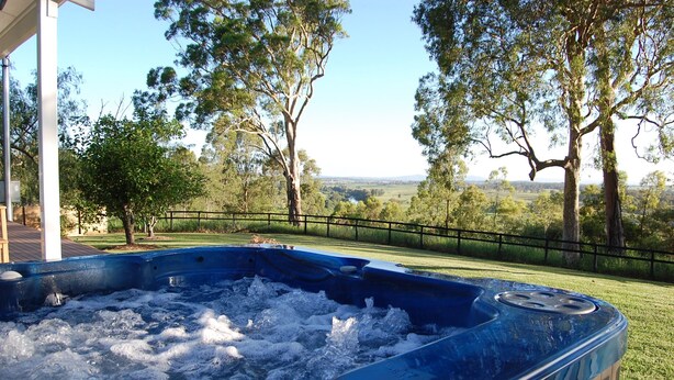 A hot tub with a view of a grassy area and trees. - Hunter Valley - Romantic luxury spa cottage - awesome views  Cadair Cottage No 2 (Rosebrook)
