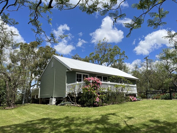 A two-story house with a white porch, surrounded by a well-maintained lawn and flowering plants.