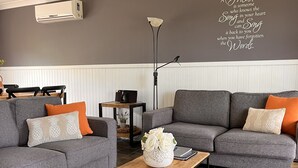 A modern living room with grey sofas, a wooden coffee table, and a decorative wall with a quote. - Hunter Valley - Romantic luxury spa cottage - awesome views  Cadair Cottage No 2 (Rosebrook)