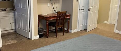 A hotel room with a bed, a desk, a chair, a television, and a bathroom.