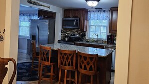 A kitchen with a central island, wooden chairs, and a dining table with chairs. - Mystic Home perfect for families- Easy walk to downtown. . (Mystic)