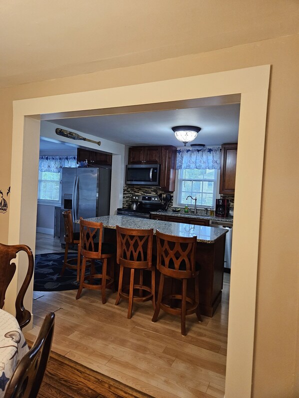 Una cocina con una isla central, sillas de madera y una mesa de comedor con sillas.