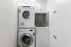 A compact laundry area with two front-loading washing machines and a built-in sink. - Hampton Lookout Rooftop Terrace with Bay Views (Hampton)