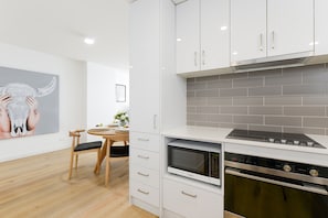 A modern kitchen with white cabinetry, a built-in oven, and a microwave. - Hampton Lookout Rooftop Terrace with Bay Views (Hampton)