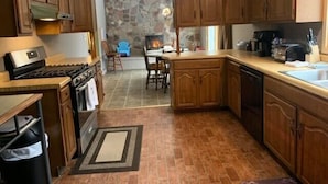 A kitchen with wooden cabinets, a stove, and a stone wall in the background.