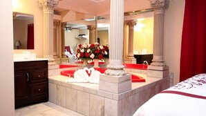 Une salle de bain d’hôtel avec un grand miroir, un lavabo en marbre et une composition florale.