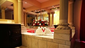 Une salle de bain luxueuse avec un lavabo en marbre, un grand miroir et une composition florale.