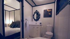 Une salle de bain moderne avec une baignoire, des toilettes et un lavabo. Un miroir est placé au-dessus du lavabo et un tableau orne le mur.