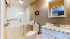 A bathroom with a glass-enclosed shower, a white toilet, and a vanity with a mirror.