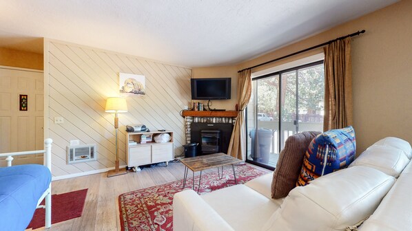 A living room with a fireplace, a television, a sofa, and a window with curtains.