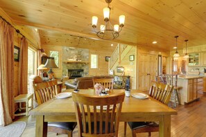 A wooden interior with a dining table, chairs, a fireplace, and a kitchen area. - Hot Tub, Fire Pit & Mtn Views: Bryson City Escape (Bryson City)