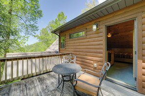 A wooden cabin with a deck, a table, and two chairs. - Hot Tub, Fire Pit & Mtn Views: Bryson City Escape (Bryson City)