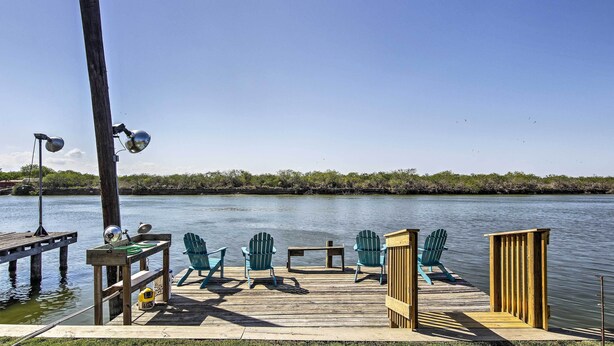 A wooden dock with chairs and a table by a calm body of water.