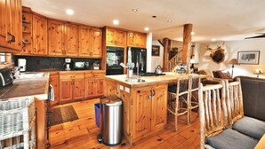 A rustic kitchen with wooden cabinets, a central island, and a deer head mounted on the wall.