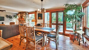 A rustic dining area with wooden furniture, a stone wall, and large windows.