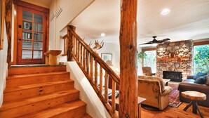 A wooden staircase with a stone fireplace and a cozy living area with a sofa and a coffee table.