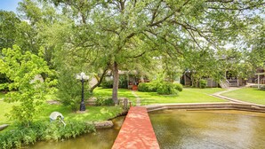 Un giardino tranquillo con uno stagno, un ponte di legno e un edificio sullo sfondo.
