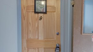 Une porte en bois portant le numéro « 9 », avec une petite photo encadrée au-dessus.