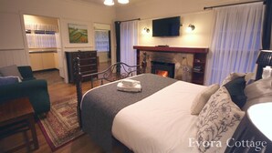 Un dormitorio con cama, chimenea, televisor y escritorio con silla.