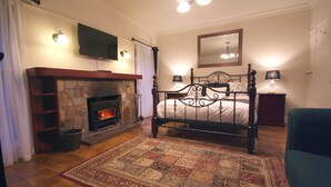 Un dormitorio con chimenea de piedra, cama con dosel, espejo grande y candelabro.