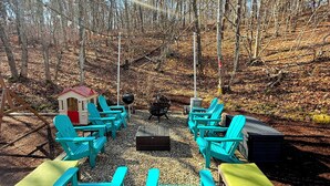 Un área de estar al aire libre con sillas Adirondack turquesa y un brasero.