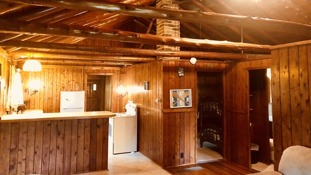 A rustic cabin interior with wooden walls and a high ceiling.