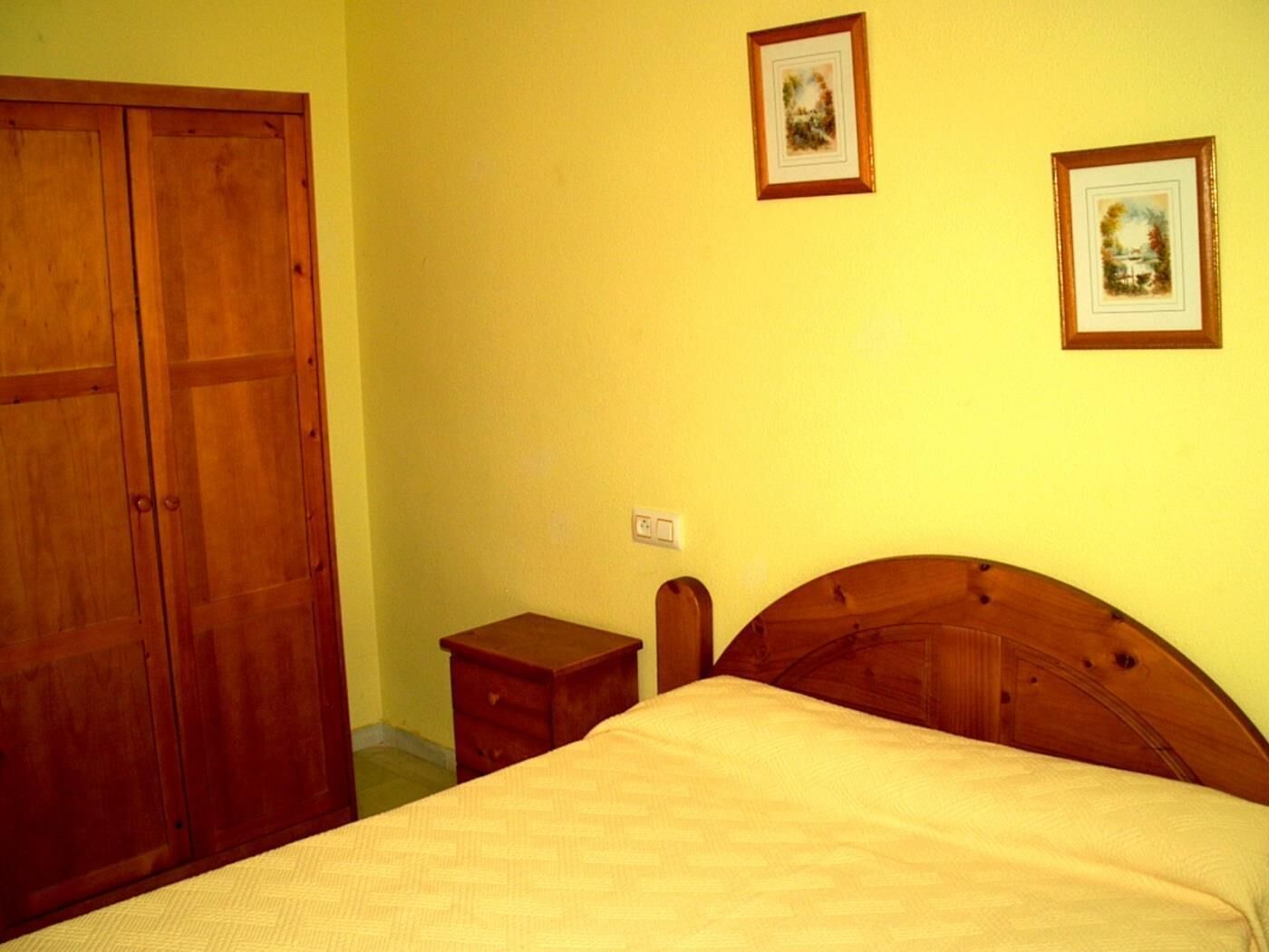 Une chambre à coucher avec un lit en bois, une table de chevet et une armoire.