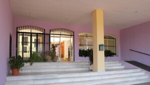 A building entrance with steps leading up to a door, a column, and potted plants. - APCOSTAS San Antonio / One Bedroom (Alcoceber)