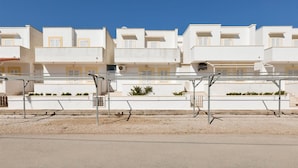 Une rangée de bâtiments blancs dotés de balcons, un ciel bleu azur et un sol pavé.