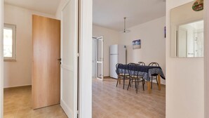 Un coin repas avec une table et des chaises, un réfrigérateur et un luminaire au plafond.