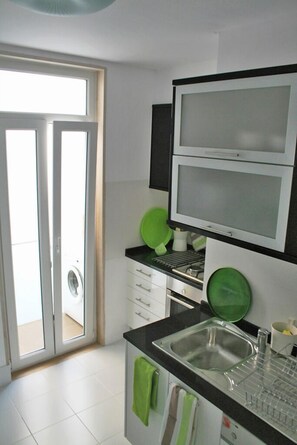 A kitchen with a double sink, a microwave, and a window with a view. - Apartment/ flat , view-point Tagus, castle, optional garage,WI-FI A/C (Lisboa)