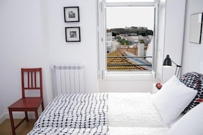 A bedroom with a bed, a chair, a radiator, and a window with a city view. - Apartment/ flat , view-point Tagus, castle, optional garage,WI-FI A/C (Lisboa)