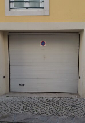 A closed garage door with a no parking sign above it.