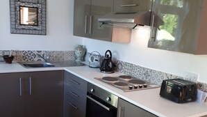 Een moderne keuken met roestvrijstalen apparatuur, een inbouwoven en een groot raam boven het aanrecht.
