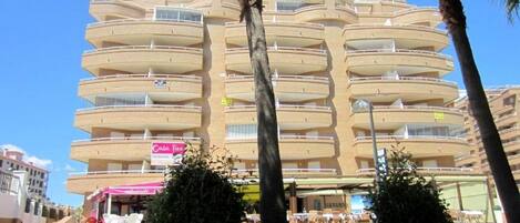 A multi-story hotel with balconies, a restaurant named "Casa Taco" on the ground floor, and palm trees in the foreground.